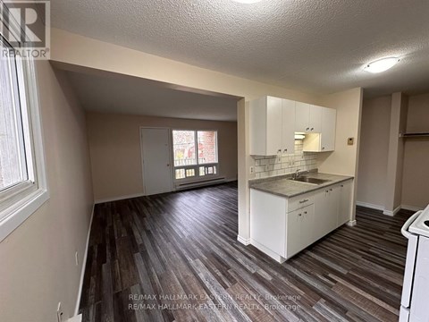 A kitchen area with white cabinets and a wooden floor.