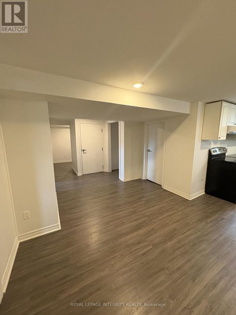 A spacious room with wooden flooring and white walls.
