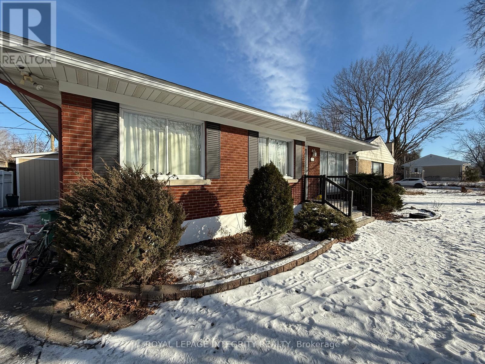 A red brick house with a white roof and a snow-covered ground.