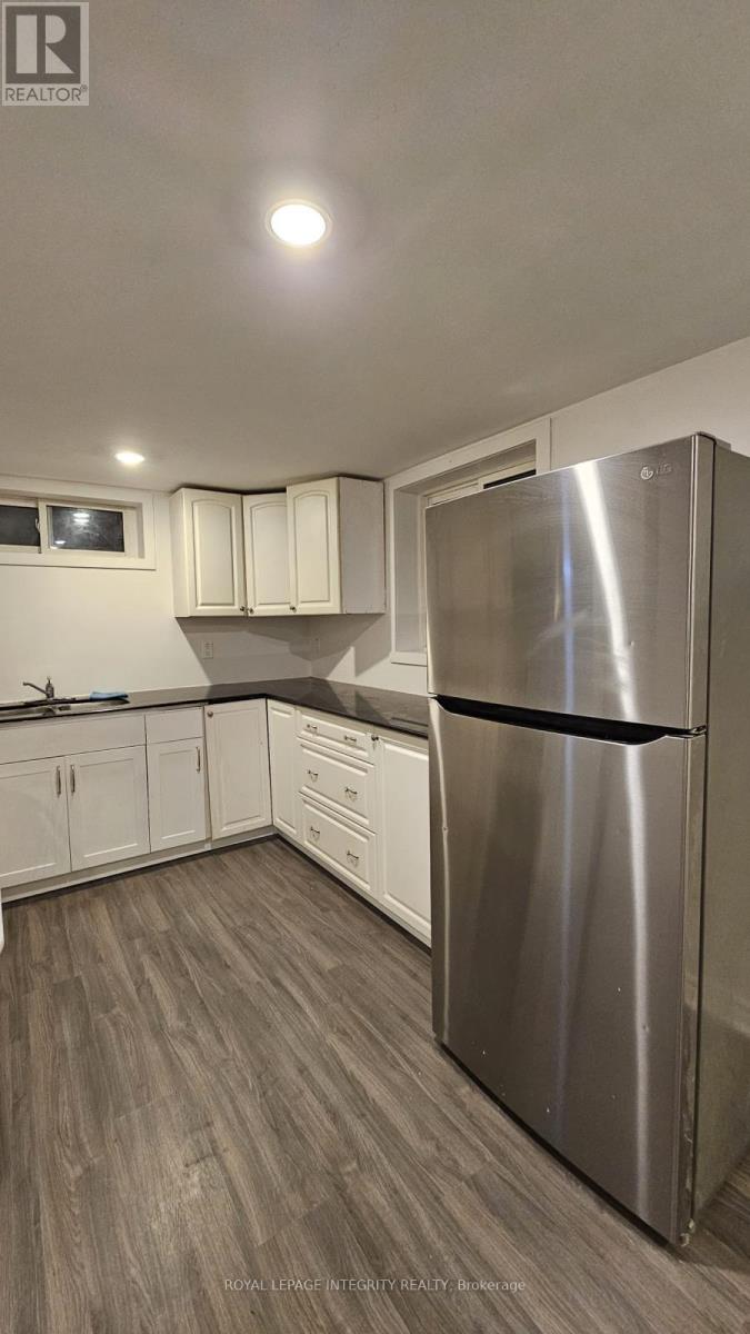 A kitchen with a stainless steel refrigerator and wooden flooring.