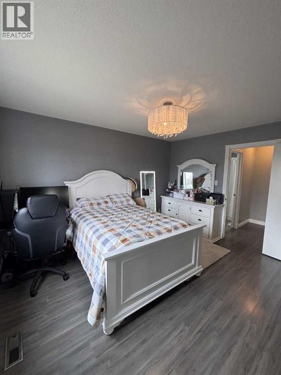 A bedroom with a bed, dresser, and chair.