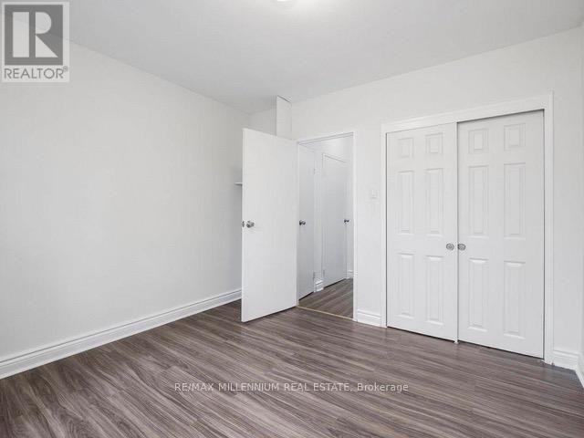 A room with white walls and a wooden floor with a brokerage logo.