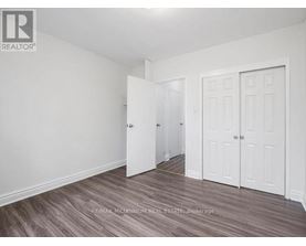 A room with white walls and a wooden floor with a brokerage logo.