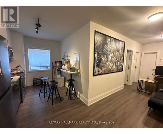 A living room with a bar stool and a painting on the wall.