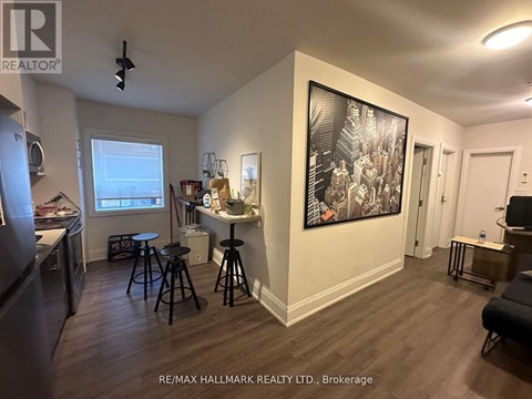 A living room with a bar stool and a painting on the wall.