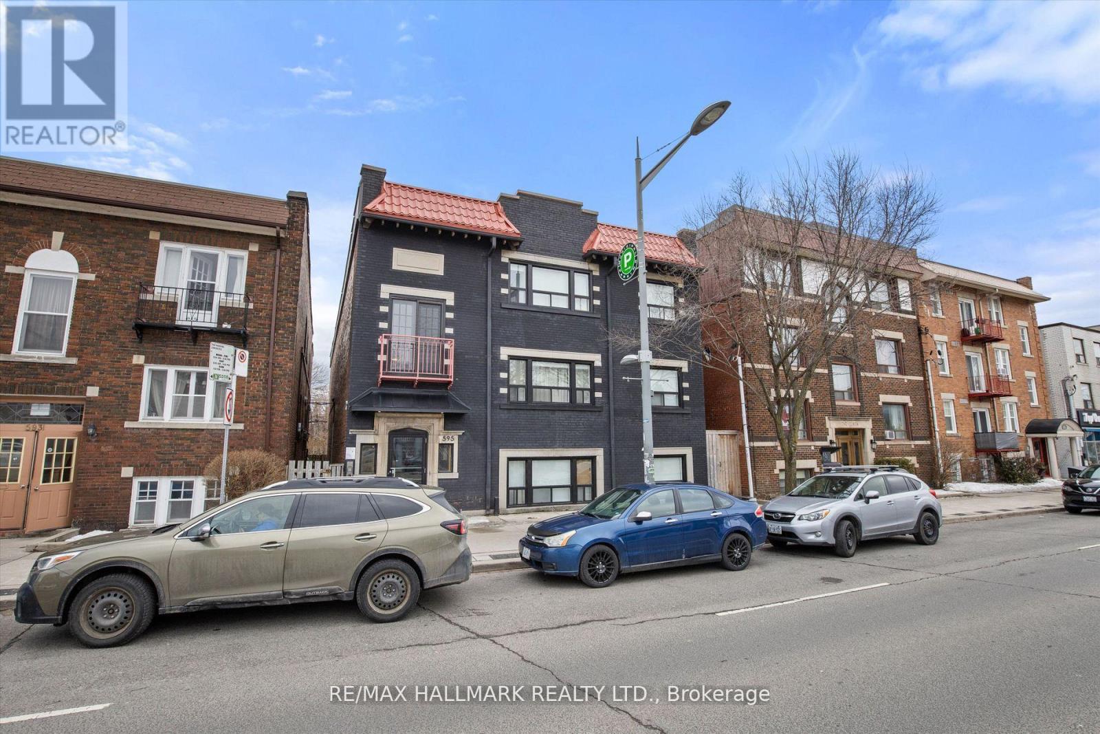 A street view with cars and buildings with a RE/MAX Hallmark Realty Ltd. logo.