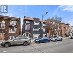 A street view with cars and buildings with a RE/MAX Hallmark Realty Ltd. logo.