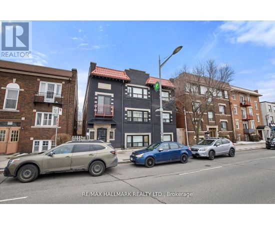 A street view with cars and buildings with a RE/MAX Hallmark Realty Ltd. logo.
