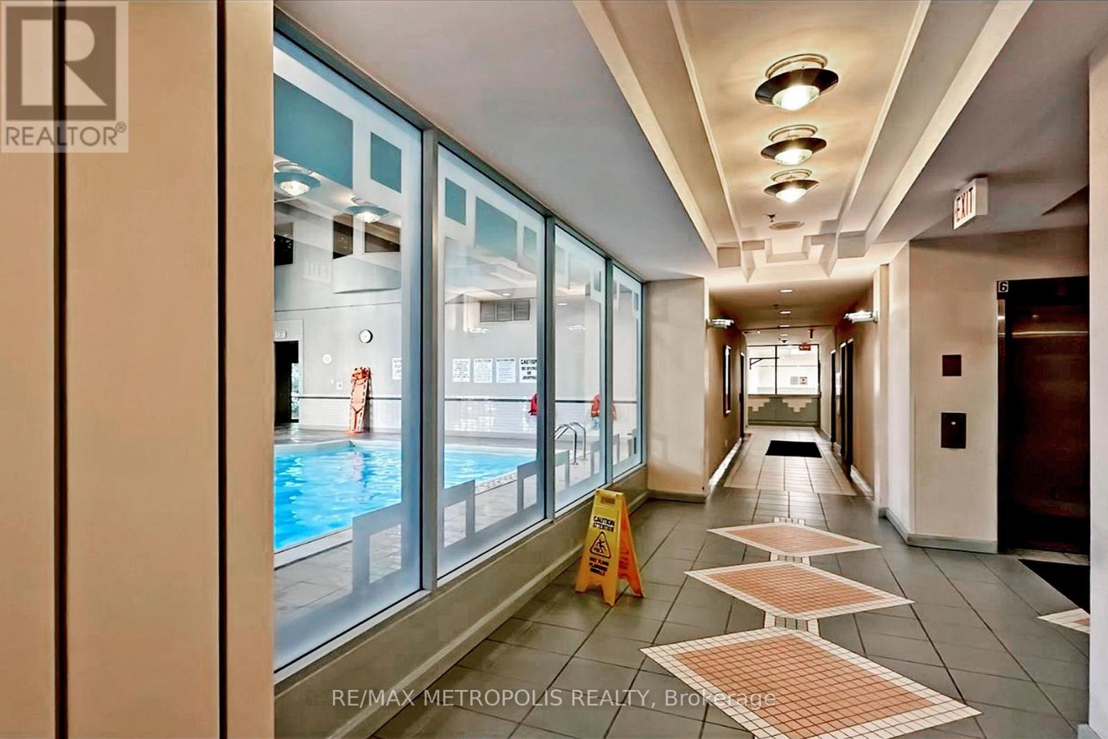 A hallway with a pool visible through the windows.
