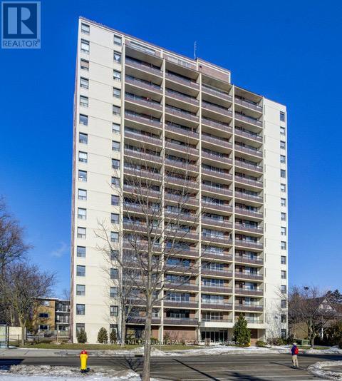 A tall white apartment building with balconies on the upper floors.