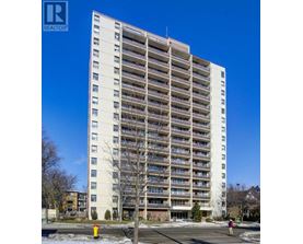 A tall white apartment building with balconies on the upper floors.