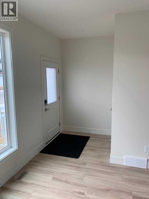 A room with a black mat on the floor and a door on the left.