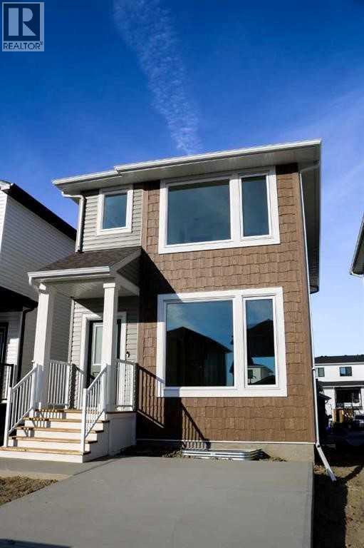A two-story house with a brown and white exterior and a black metal railing on the front porch.
