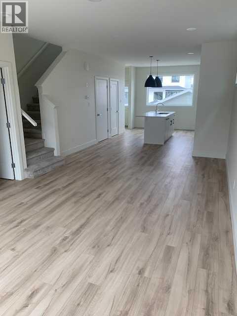A spacious room with wooden flooring and white walls.
