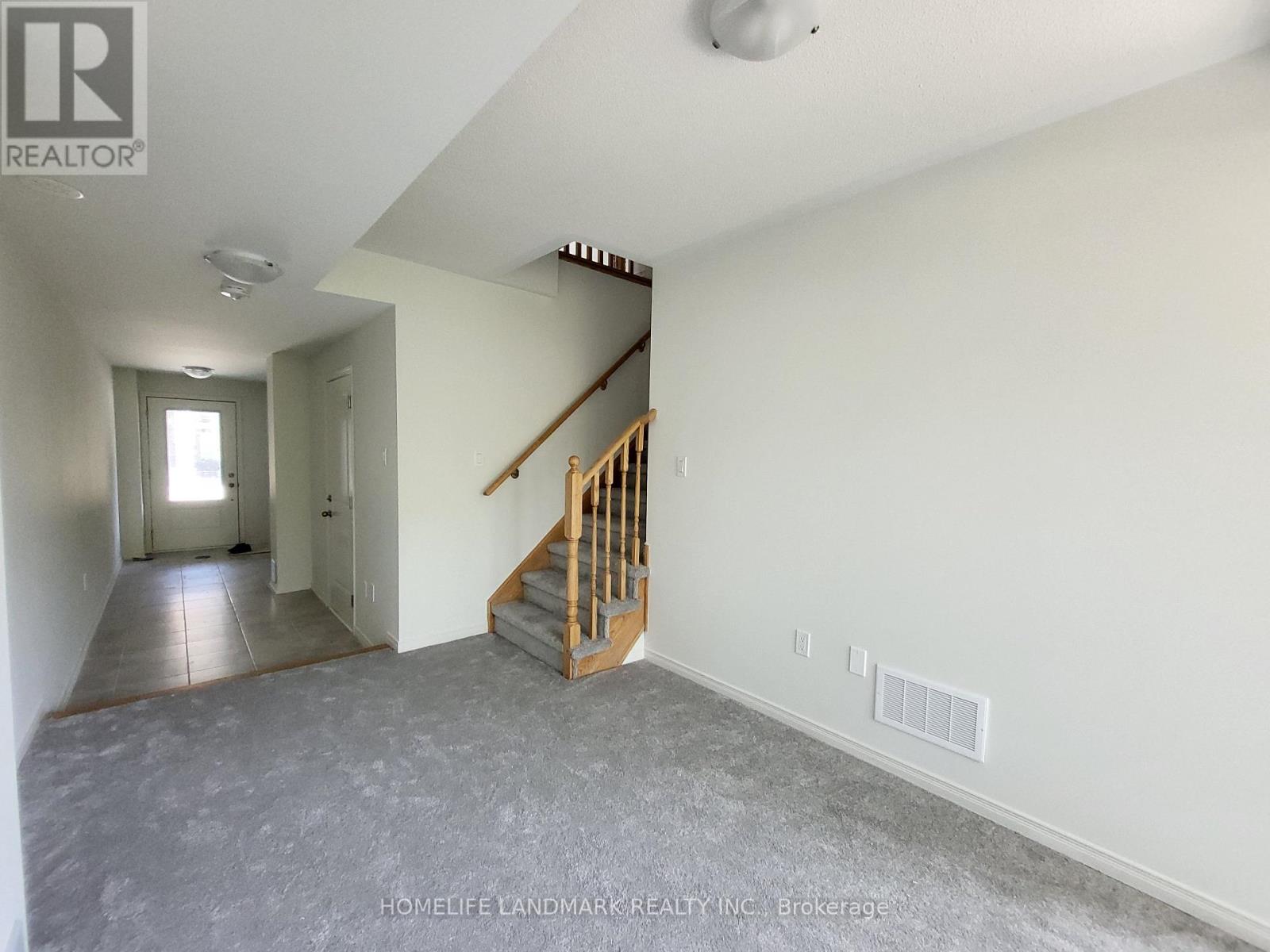 A spacious room with a staircase leading to the upper level.