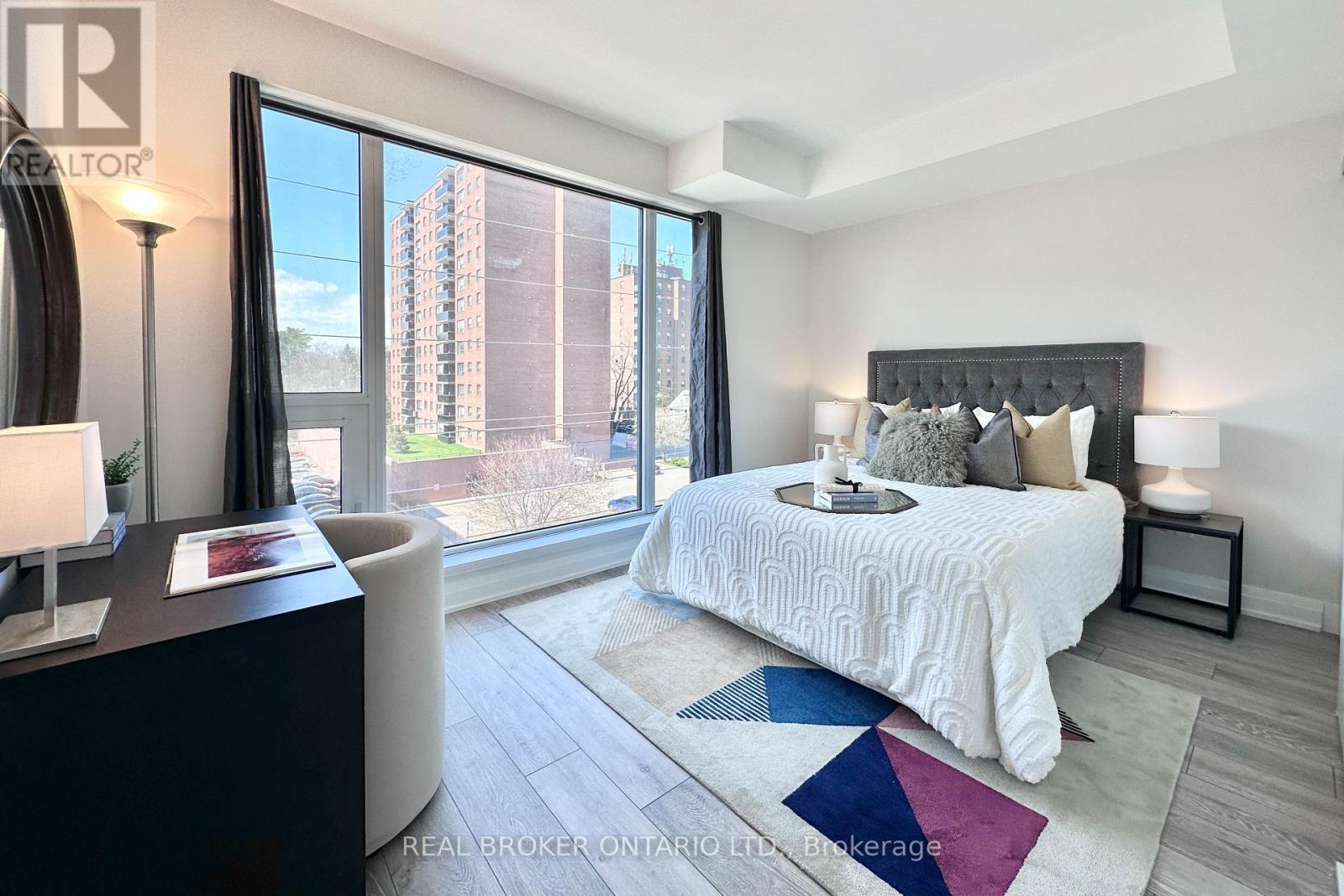 A bedroom with a large bed and a view of a building outside the window.