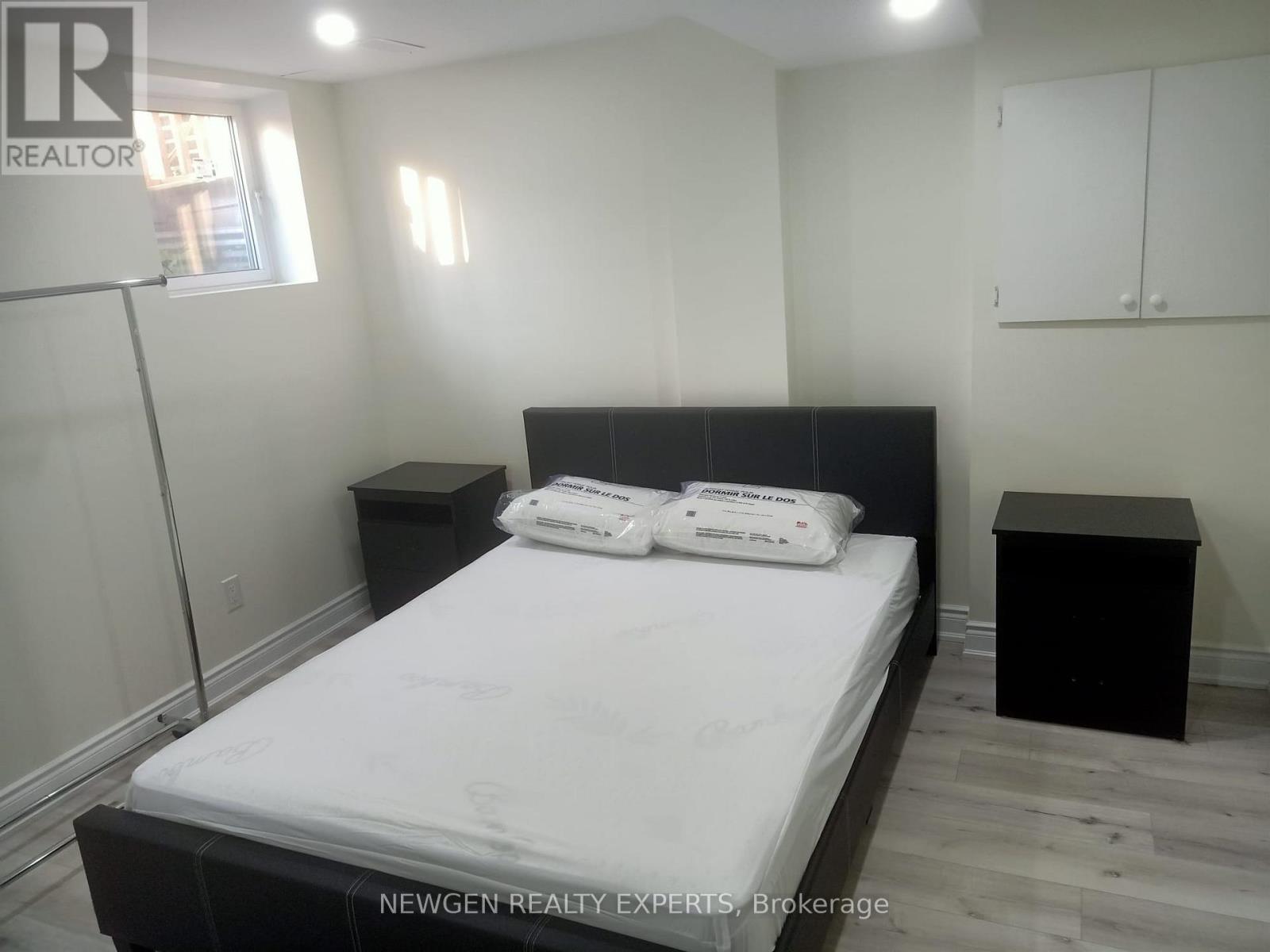 A bedroom with a bed, nightstand, and a cabinet.