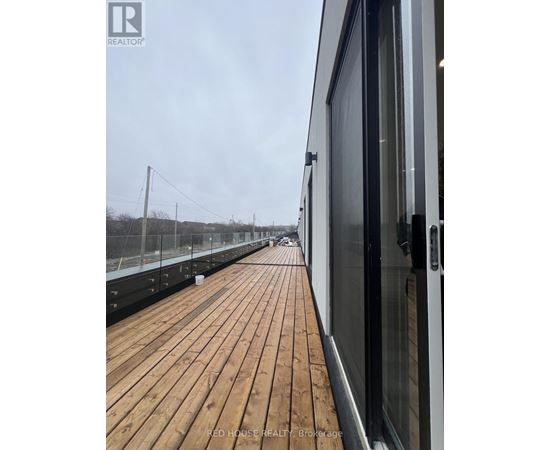 A wooden deck with a glass door on the right side.