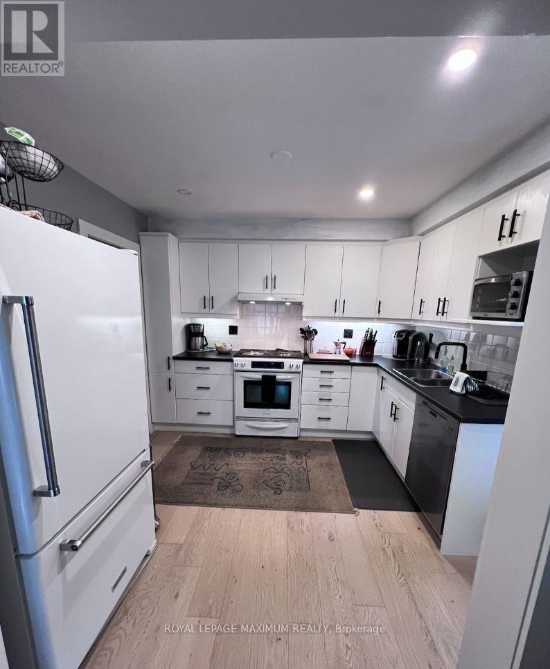 A kitchen with white cabinets and a white fridge.