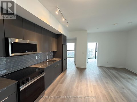 A modern kitchen with dark wood cabinets and stainless steel appliances.