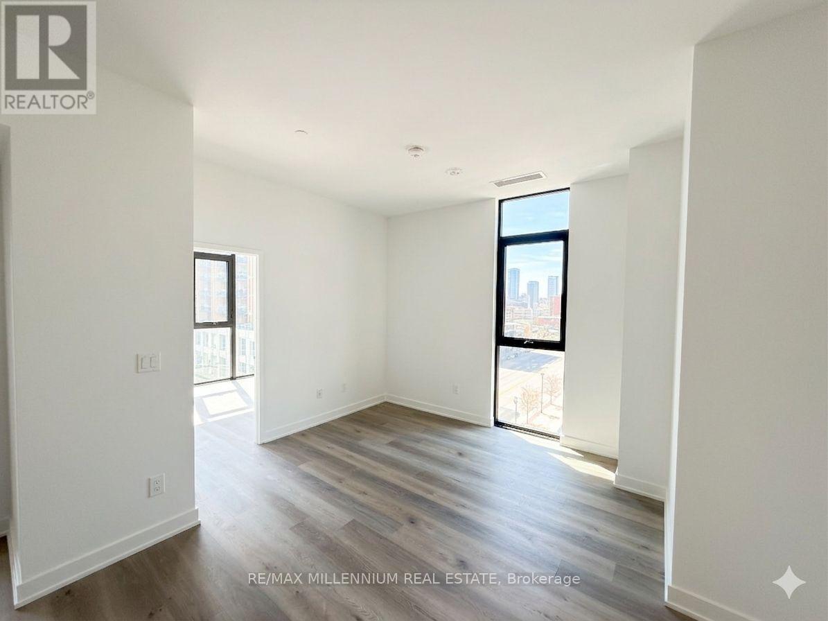 A spacious room with wooden flooring and white walls.