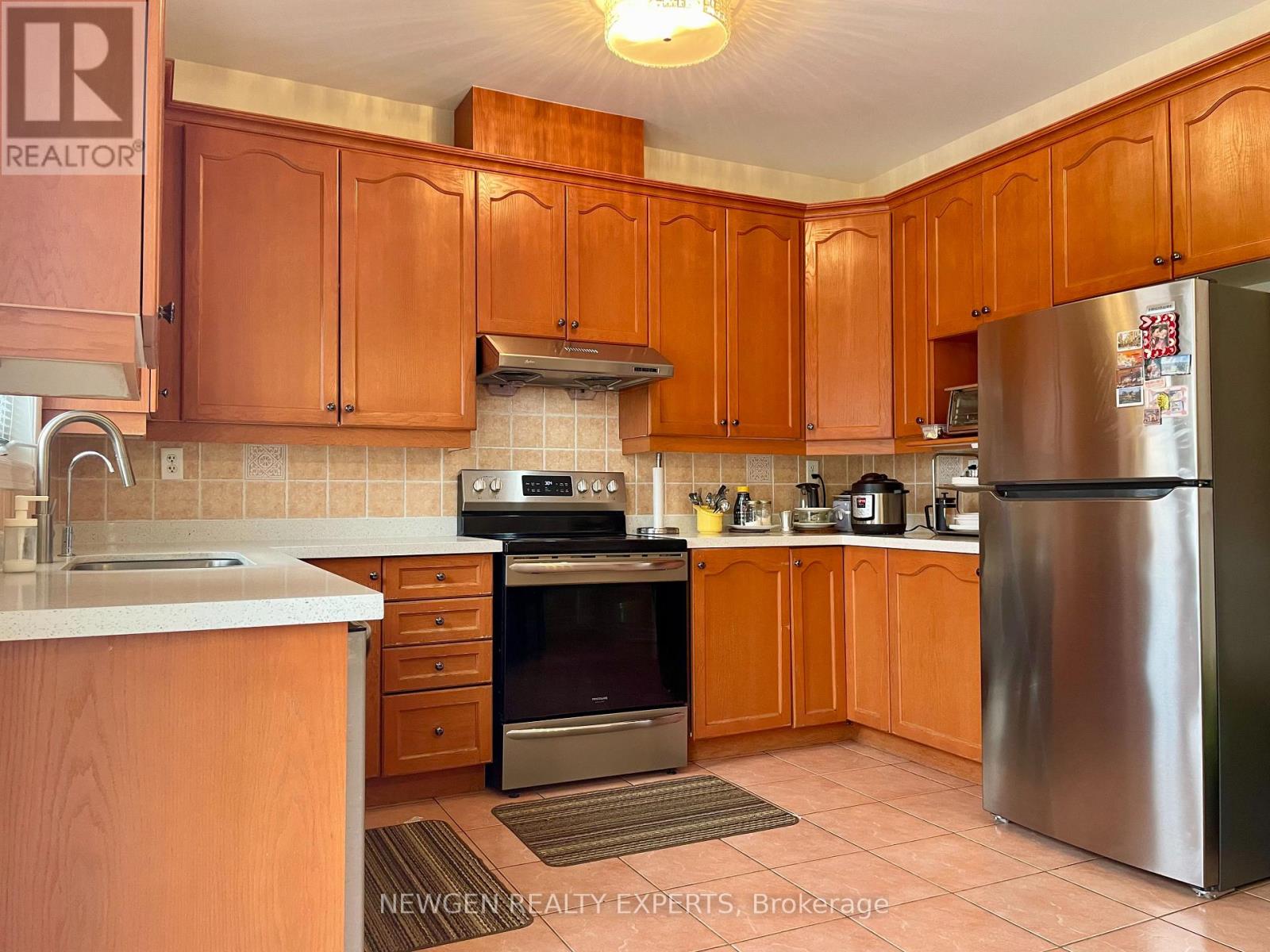 A kitchen with wooden cabinets and a stainless steel refrigerator.