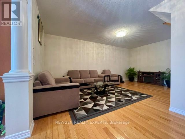 A living room with a brown couch and a black and white rug.