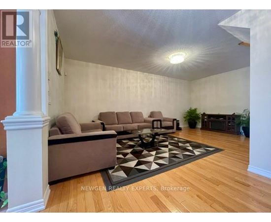 A living room with a brown couch and a black and white rug.