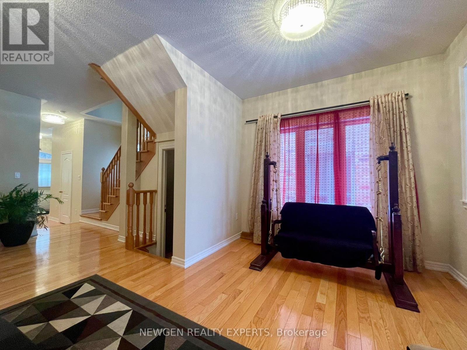 A bedroom with a bed, a window with curtains, and a rug on the floor.