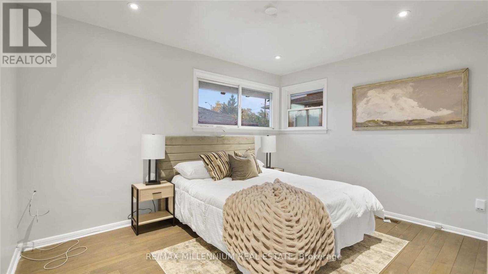 A bedroom with a large bed and a painting on the wall.