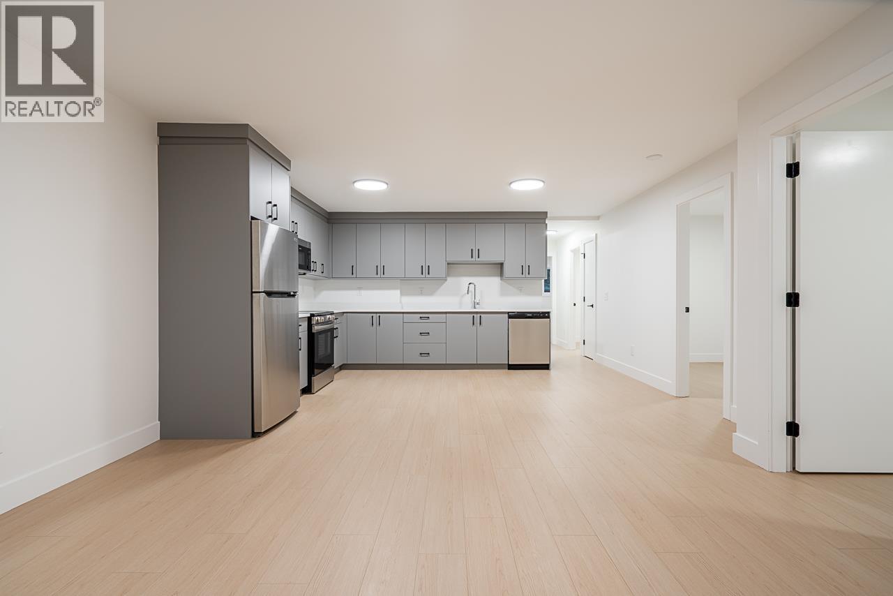 A modern kitchen with wooden floors and stainless steel appliances.