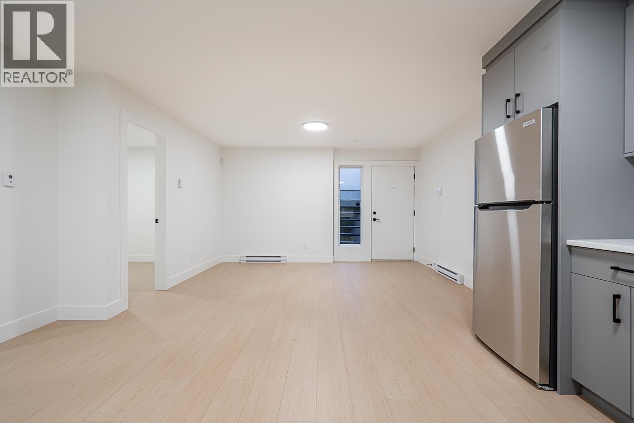 A spacious kitchen with a refrigerator and wooden flooring.