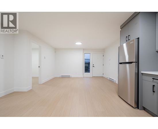 A spacious kitchen with a refrigerator and wooden flooring.