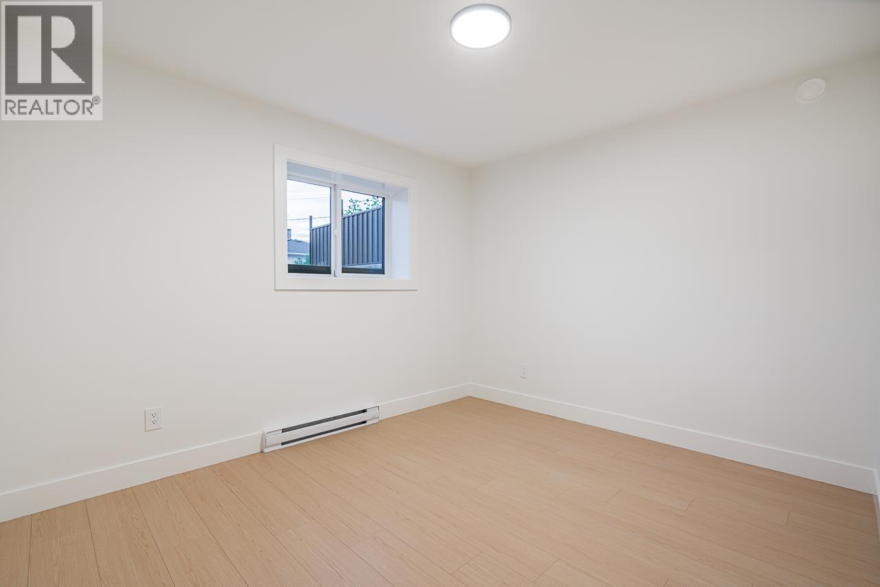 A white room with a window and a wooden floor.