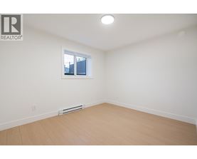 A white room with a window and a wooden floor.