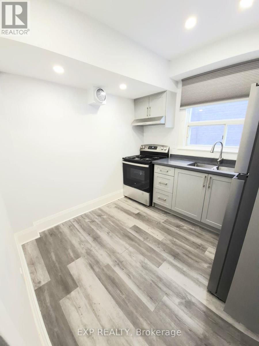 A kitchen with a black fridge, black oven, and a window with blinds.