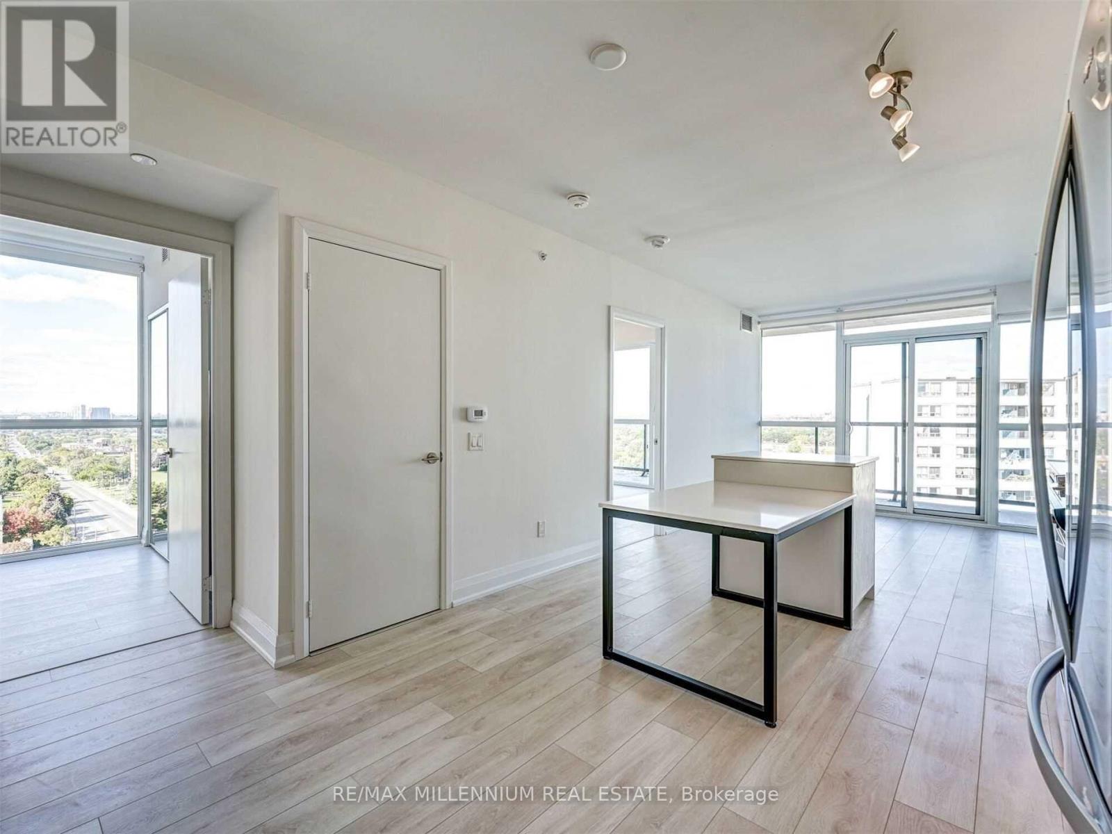 A spacious room with a desk and a large window overlooking a cityscape.