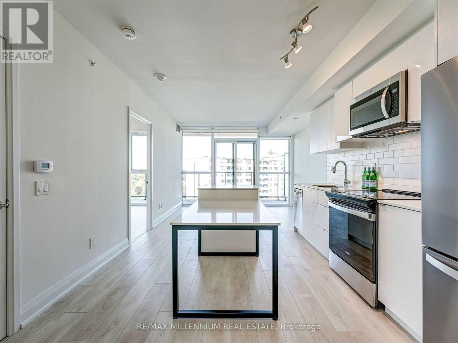 A kitchen with white cabinets and a black fridge.