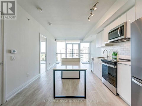 A kitchen with white cabinets and a black fridge.