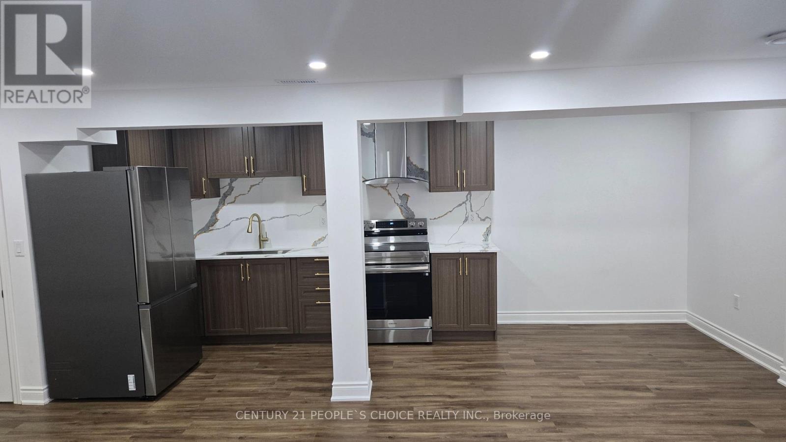 A kitchen with a refrigerator, sink, and cabinets.