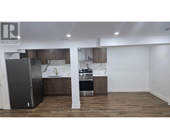 A kitchen with a refrigerator, sink, and cabinets.