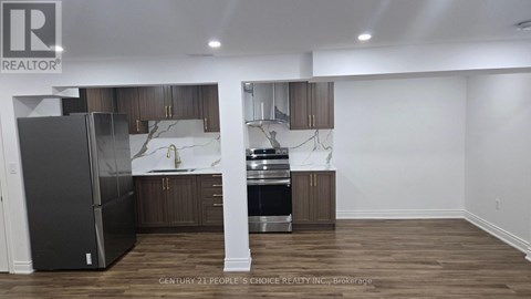 A kitchen with a refrigerator, sink, and cabinets.