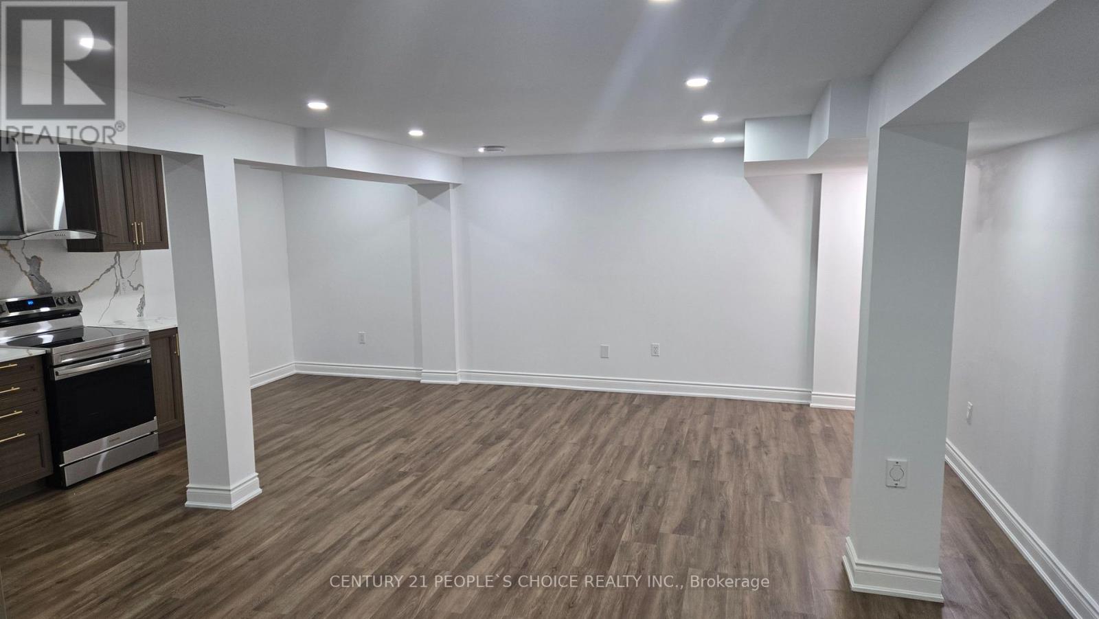A spacious room with wooden flooring and white walls.