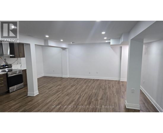 A spacious room with wooden flooring and white walls.