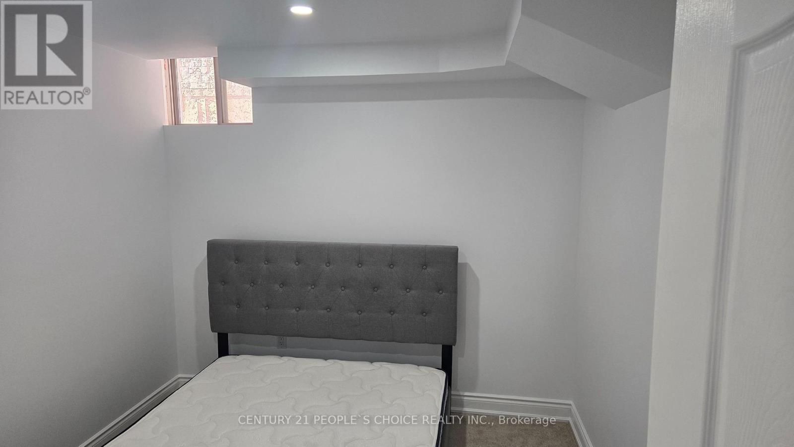 A bed with a grey headboard in a white room.