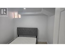 A bed with a grey headboard in a white room.