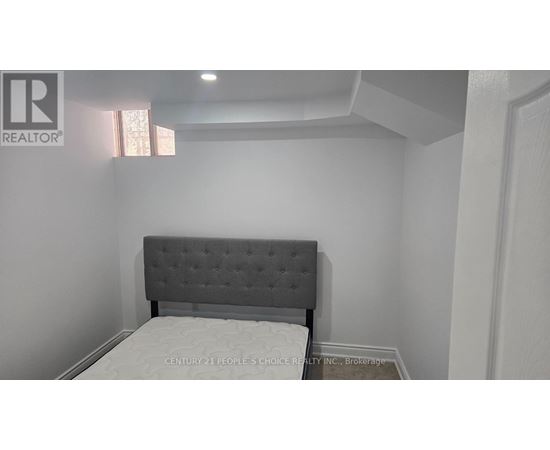A bed with a grey headboard in a white room.