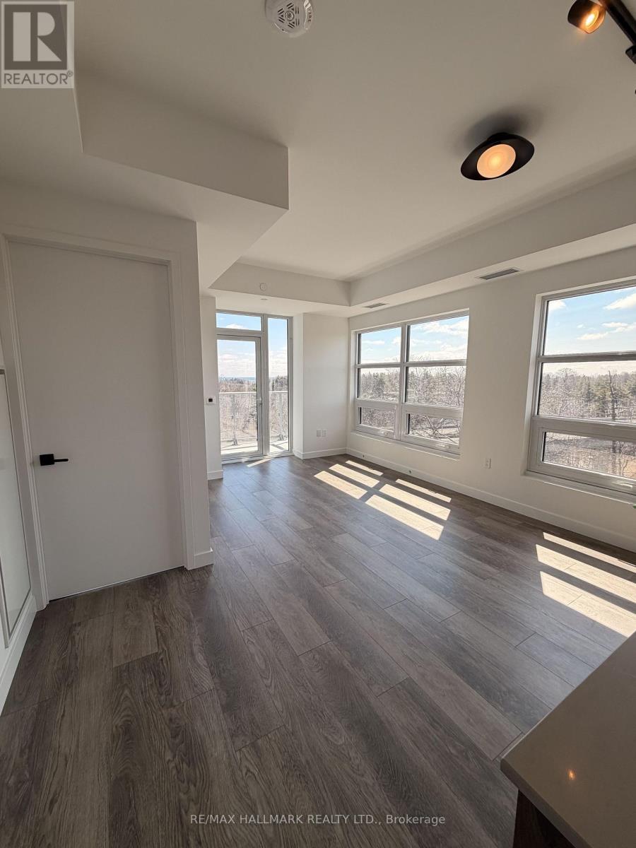A spacious room with a large window and a door leading to another room.