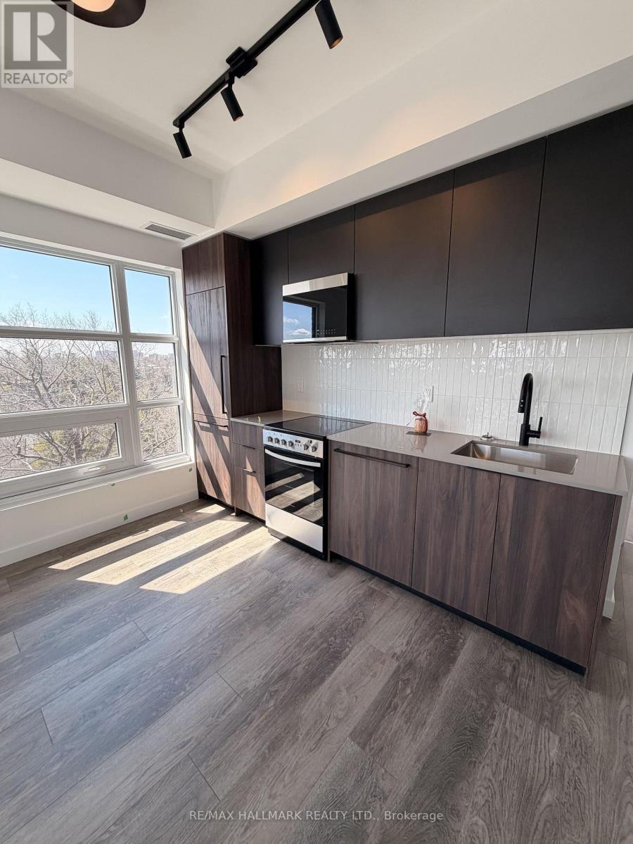 A modern kitchen with dark wood cabinets and a large window.