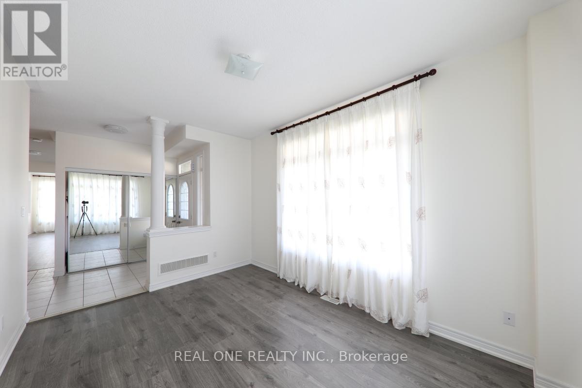 A spacious room with white walls and a large window with white curtains.